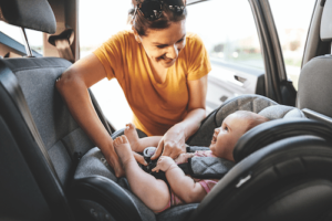 Mom putting baby in car seat